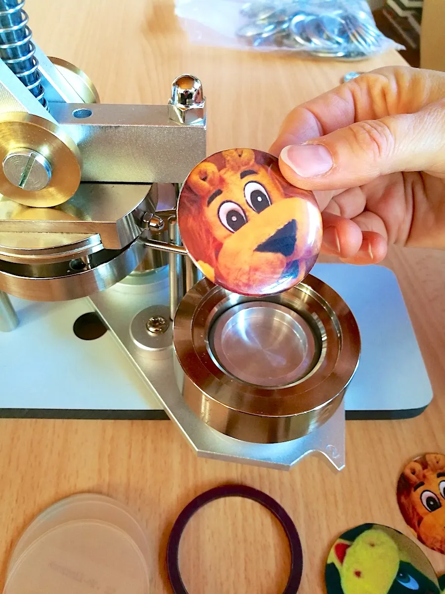 Ansteck-Button mit Löwe-Leo-Motiv wird an der Buttonpresse eingelegt