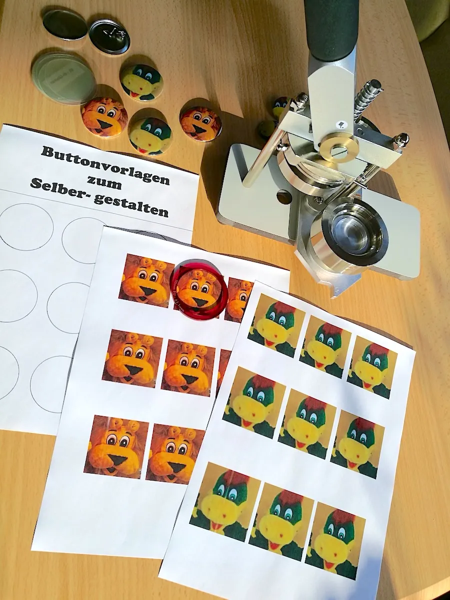 Buttonpresse mit Vorlagen und fertigen Ansteck-Buttons mit Löwe-Leo-Motiv
