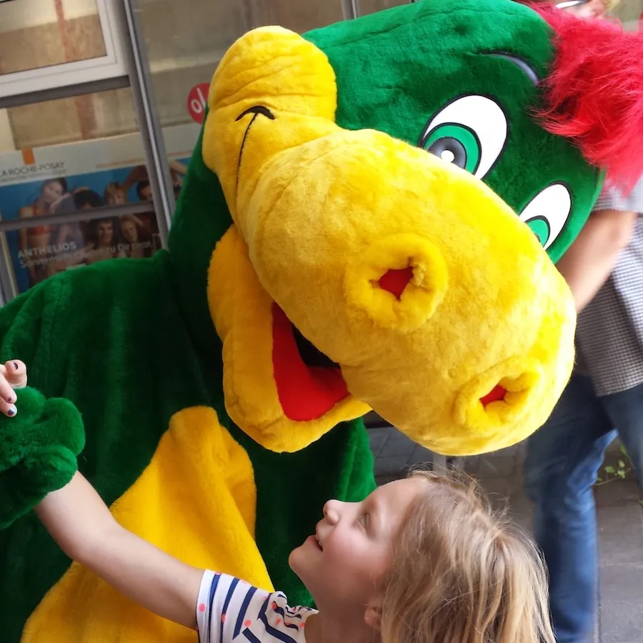 Mädchen streichelt das Maul von Drache Dinoli