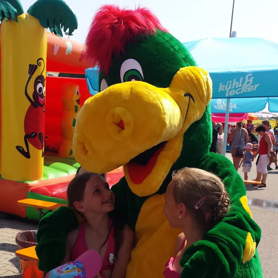Zwei Mädchen schmiegen sich auf einem Fest an Drache Dinoli