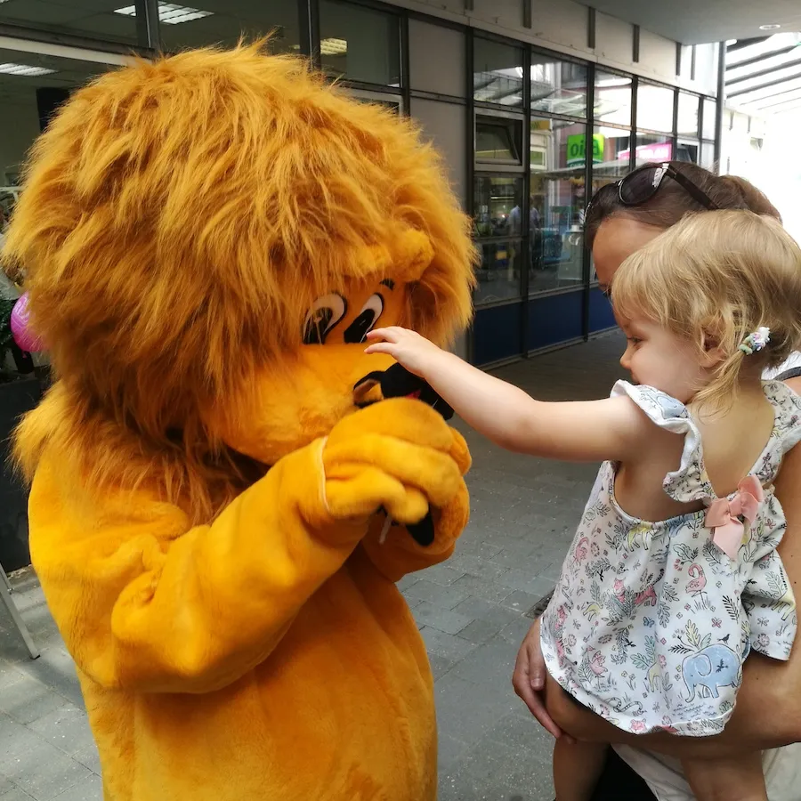 Kleines Mädchen stupst Löwe Leo zur Begrüßung an die Nase