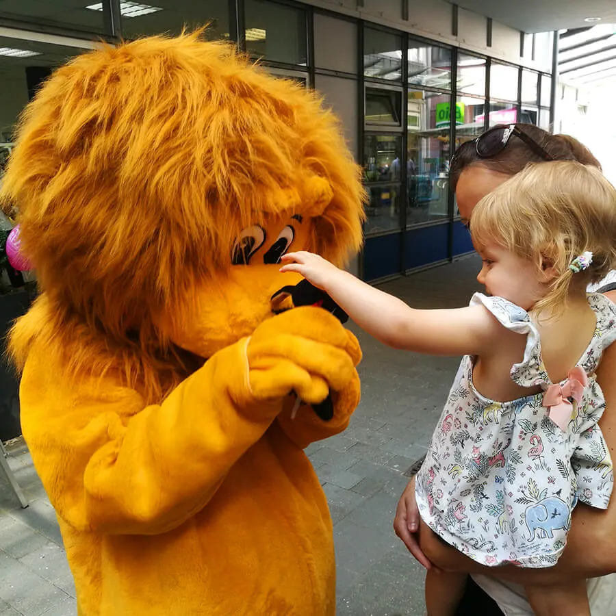 Kleines Mädchen stupst Löwe Leo an die Nase